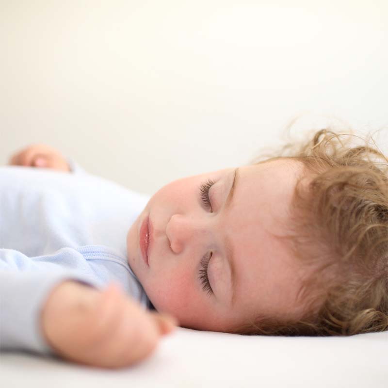 Baby sleeping on back in cot