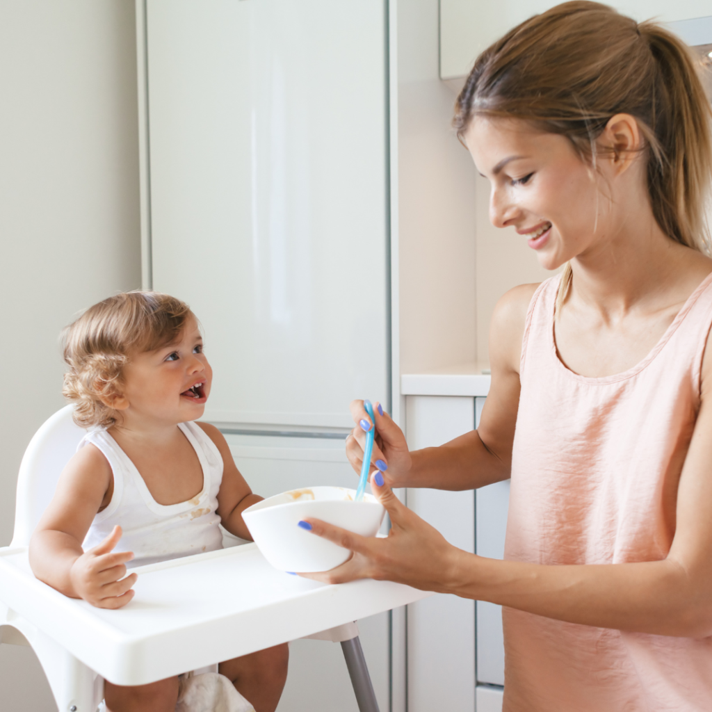 Happy mum feeding happy toddler in high chair