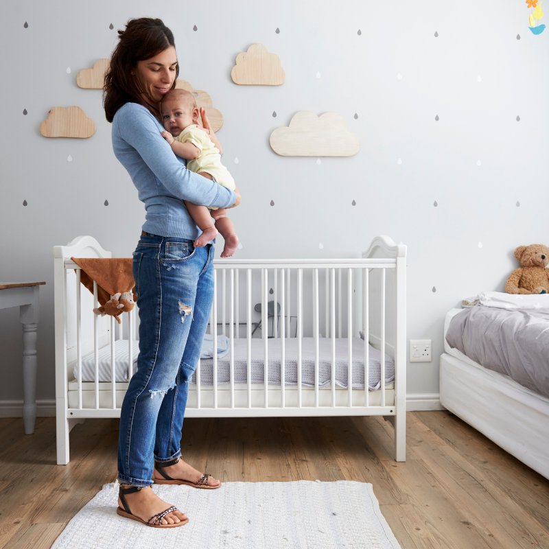 Mum holding baby in nursery next to cot